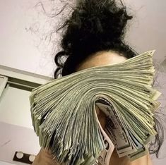 a woman holding money in front of her face, with the hair pulled back into a bun