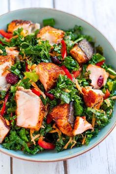 a bowl filled with meat and vegetables on top of a white wooden table next to a fork