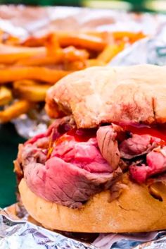 a roast beef sandwich and french fries on tin foil