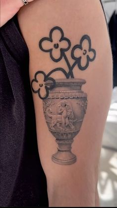 a black and white photo of a woman's arm with flowers in a vase