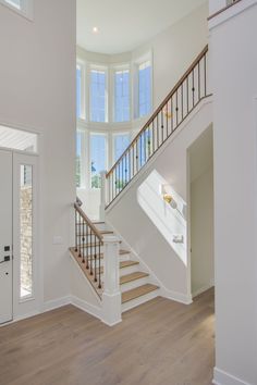 an empty room with white walls and wood floors, stairs leading up to the second floor