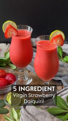 two glasses filled with fruit and garnish on top of a wooden table next to strawberries