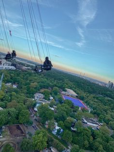 an aerial view of some people riding on a ski lift over the trees and buildings