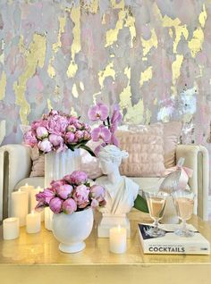 a living room with pink flowers and candles on the coffee table in front of it