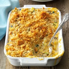 a casserole dish with chicken and cheese in it on a wooden table next to a blue towel