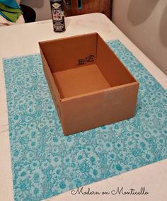 an open cardboard box sitting on top of a table next to a bottle of alcohol