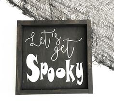 a sign that says let's get spooky in white lettering on a black frame