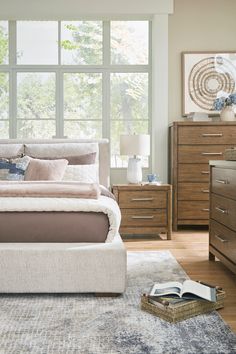 a bedroom with a bed, dressers and large windows in it's center