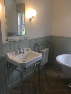 a white sink sitting next to a bath tub in a bathroom under a mirror on the wall