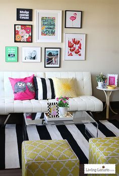 a white couch sitting in front of a wall filled with pictures and framed art on it