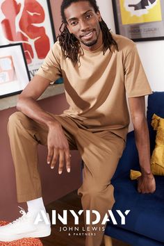 a man with dreadlocks sitting on a blue couch in front of a painting