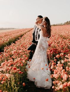 a bride and groom standing in a field of flowers