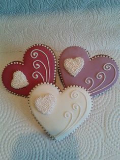 three heart shaped cookies sitting on top of a bed