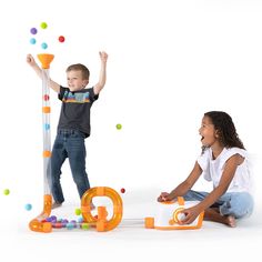 two children playing with letters and balls on the floor in front of a white background