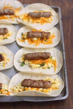 breakfast burritos with eggs, sausage and cheese on a baking sheet ready to go into the oven