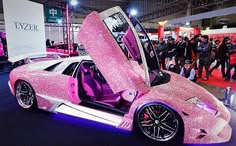 a pink car with its doors open on display