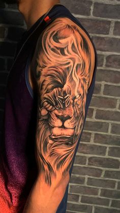 a man's arm with a lion tattoo on it, next to a brick wall