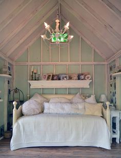 a white bed sitting under a chandelier in a bedroom