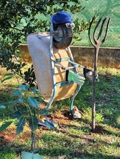 an old chair sitting in the grass next to a tree with a hat on it