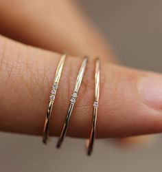 a woman's hand with three different rings on her finger and one is holding the other