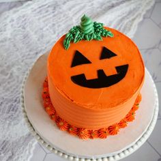 an orange cake with a jack - o'- lantern face on top sits on a white plate