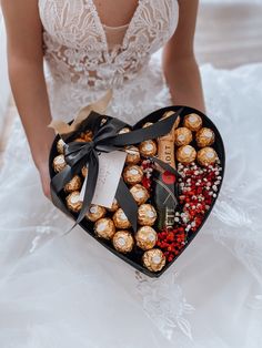 a woman holding a heart shaped box filled with chocolates and candies in it