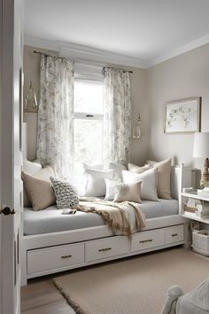 a white day bed sitting in a bedroom next to a window filled with pillows and blankets