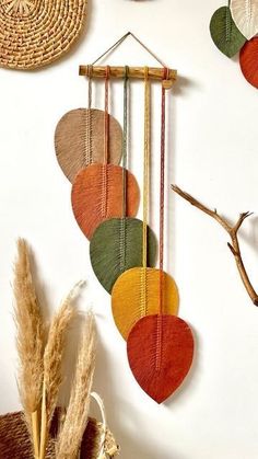 a wall hanging made out of different colored circles and sticks, next to some dried plants