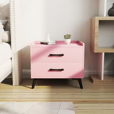 a pink chest of drawers next to a white bed