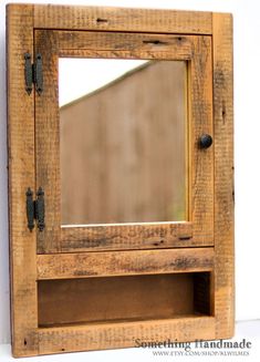 an old wooden mirror is hanging on the wall next to a white wall and black knobs