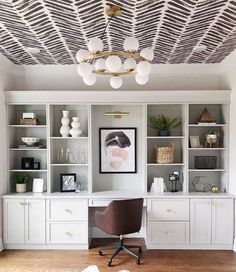 an office with white bookcases, shelves and a cowhide rug on the floor