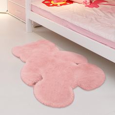 a pink teddy bear rug on the floor next to a bed