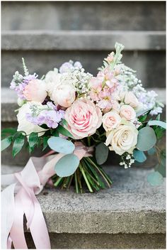 a bouquet of flowers sitting on top of a stone step next to a pink ribbon