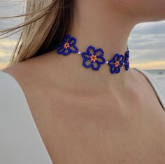 a close up of a woman wearing a necklace with blue and orange flowers on it