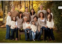 a family is posing for a photo in the park on a bench with their children