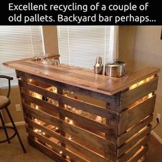 a bar made out of wooden pallets with lights on the top and two stools