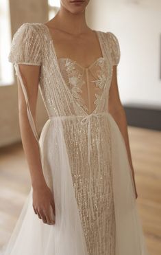 a woman in a white dress standing on a wooden floor with her hands behind her back