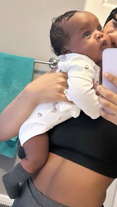 a woman holding a baby in her arms and taking a selfie with the camera