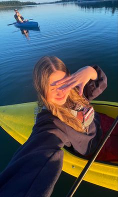 a woman sitting on top of a yellow kayak in the middle of a lake