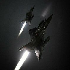 two fighter jets flying through the air at night