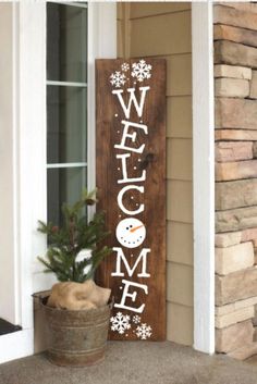 a welcome sign on the front door of a house with a potted plant next to it