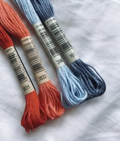 three skeins of yarn sitting on top of a white cloth covered tablecloth