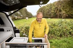 an older man is looking into the open trunk of his truck