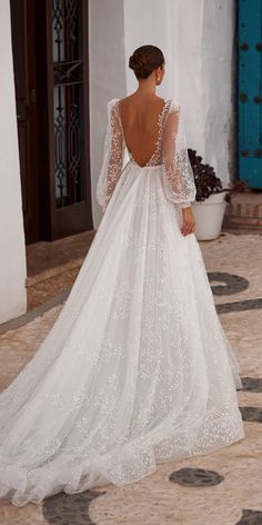 a woman in a white wedding dress is walking down the street with her back to the camera