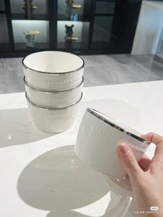 a hand is holding a coffee cup on a table with other cups in the background