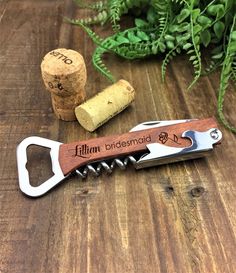 a bottle opener and corkscrew on a wooden table next to some green plants