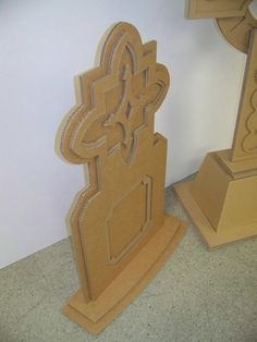 two sculptures made out of cardboard sitting next to each other on the floor in front of a white wall