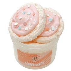 two cookies in a plastic container with pink frosting and sprinkles