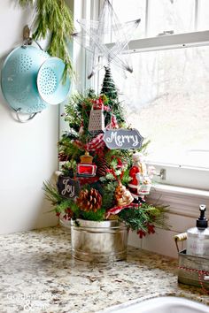 a christmas tree decorated with wooden signs and pine cones in a bucket next to a window