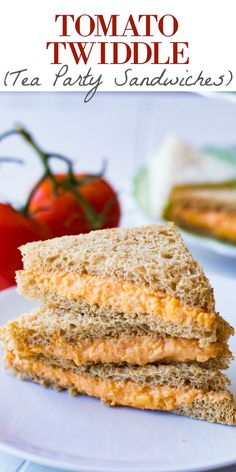 two sandwiches stacked on top of each other on a white plate with tomatoes in the background